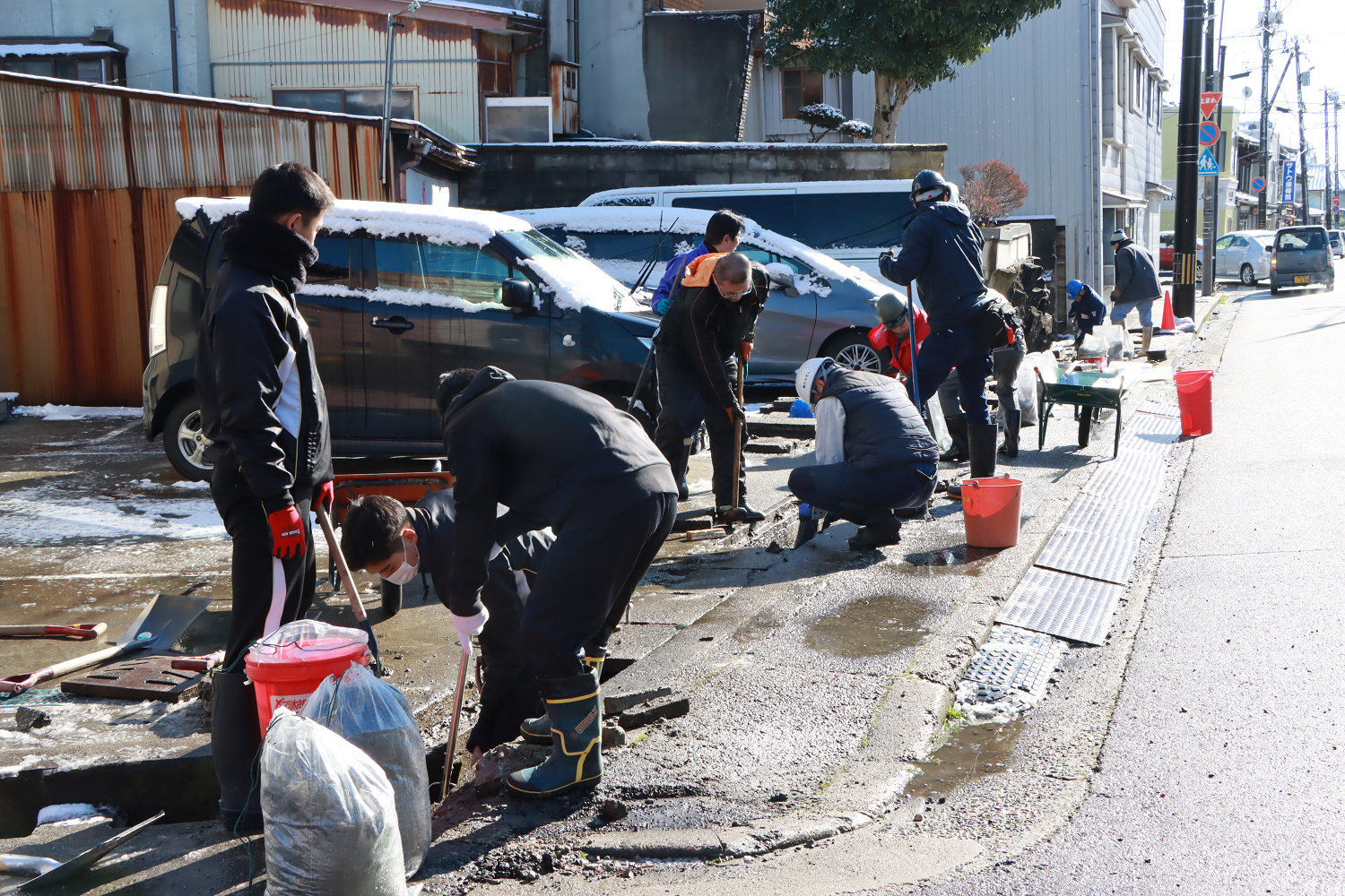 地元住民らと協力し、側溝の泥のかき出し作業を行う様子