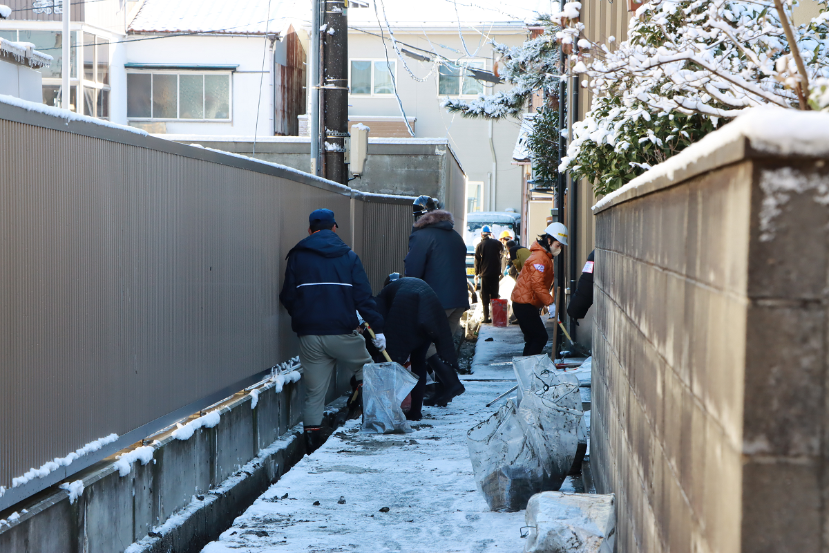 地元住民らと協力し、側溝の泥のかき出し作業を行う様子