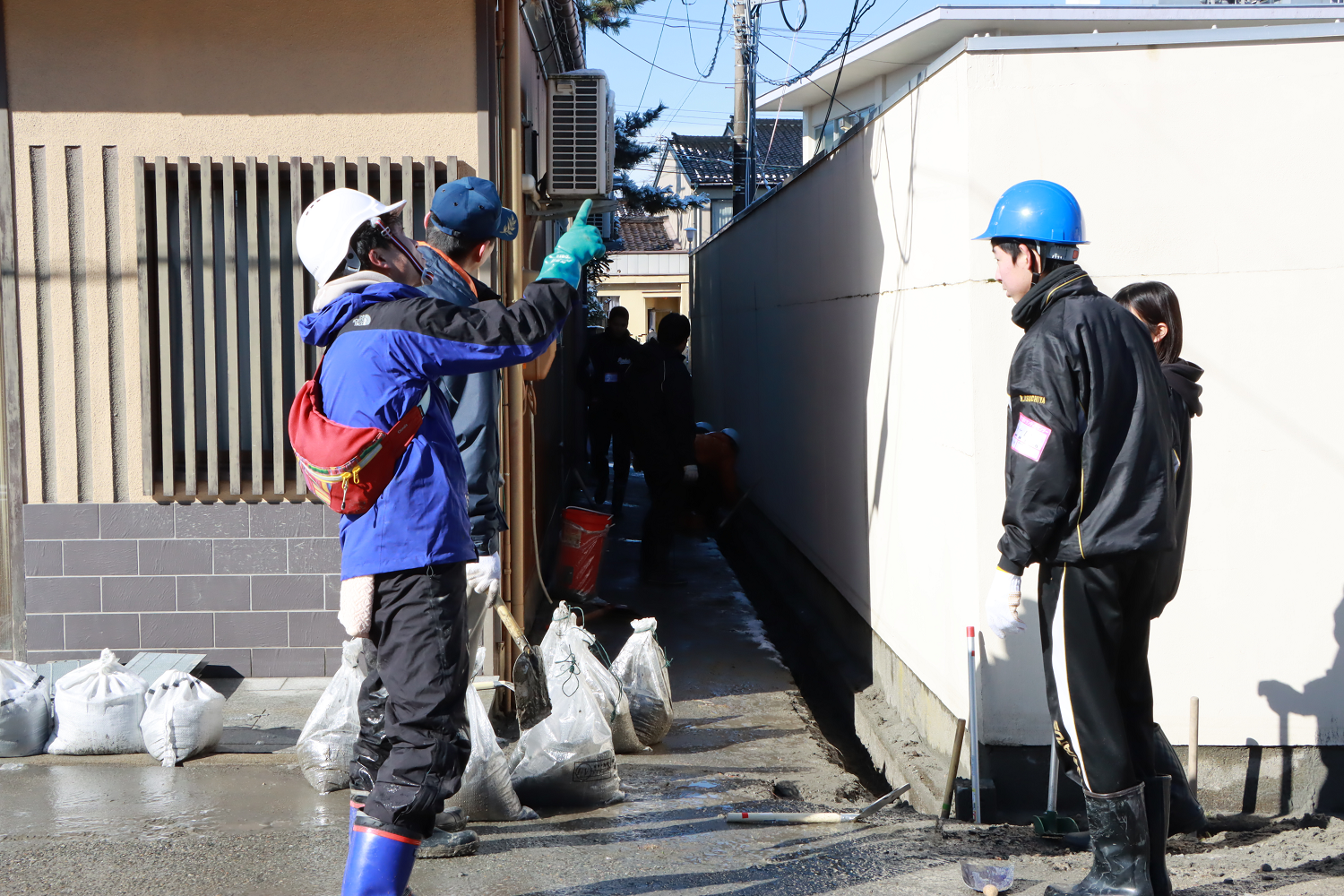 地元住民らと協力し、側溝の泥のかき出し作業を行う様子