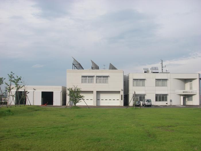 芝生の広場前に建つ白い建物の写真