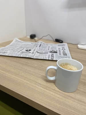 カウンターテーブルに新聞紙とコーヒーが置かれた写真