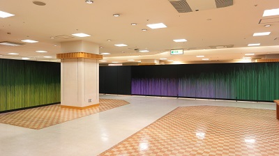 緑色と紫色のカーテンがかかり、奥に白い柱が建っている部屋の写真