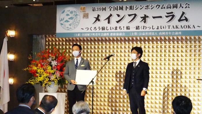 株式会社ナガエの長柄洋一さんと1人の男性が壇上に立ち、長柄洋一さんが賞状を手にしている様子を写した写真