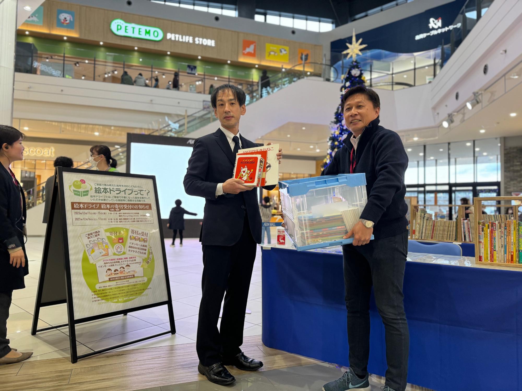 イオンモール高岡にて、高岡地区リサイクル協議会の安田会長から絵本の寄付を受けるイオンモール高岡の中谷ゼネラルマネージャー
