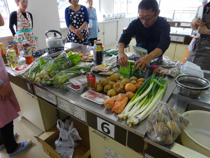 調理室のグレーの机の上の食品で料理をしようとしている男性の写真