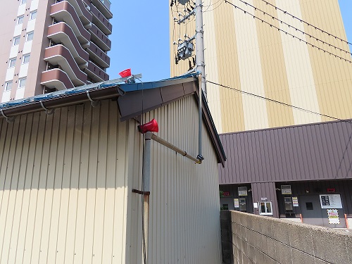 建物の軒周りに設置された、音声装置のスピーカーの写真
