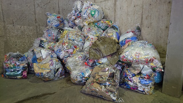 プラスチック容器包装ごみの選別過程で除去された、異物入り袋の山の写真