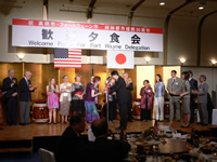 アメリカと日本の国旗が掲げられた壇上のマイクの前で2人が向かい合っている写真