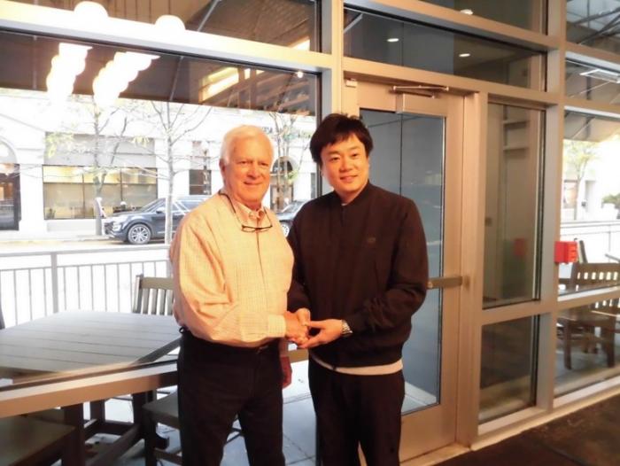 テラスのある建物の中で握手をしている2人の男性の写真
