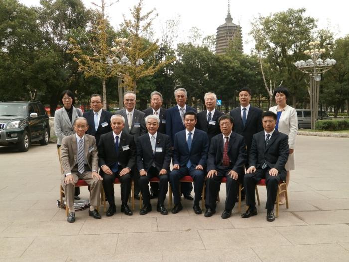 遠くに寺院が見える公園で並んでいるスーツ姿の男女の写真