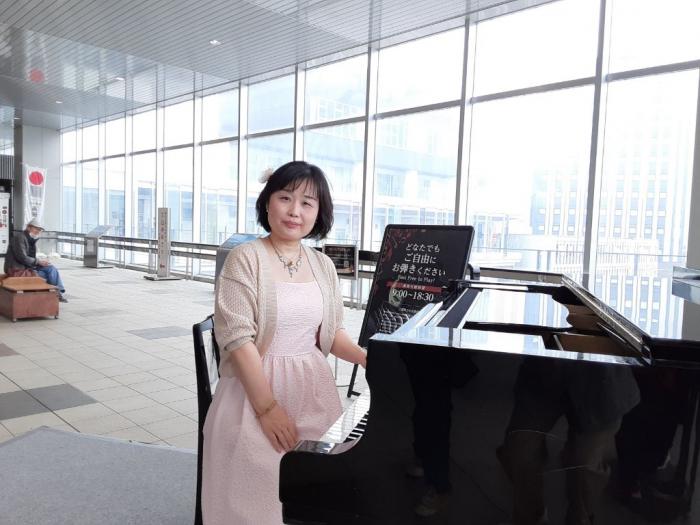 ピアノを前に着席して撮影に応じる石見由美子女史の写真