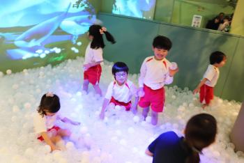 クジラや妖精などの映像が投影されたボールプール「バブリン」で遊ぶ5人の子どもを写した写真