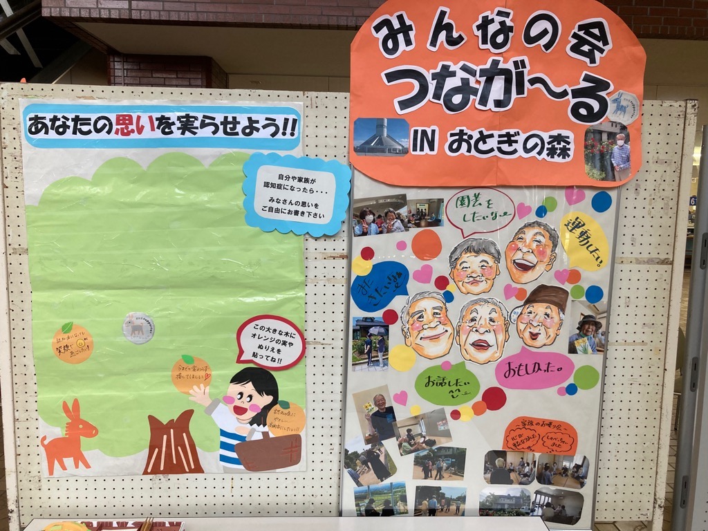 「みんなの会 つなが~る in おとぎの森」と書かれた紙が貼ってあり、写真やイラスト、参加者のコメントが掲載されている展示板
