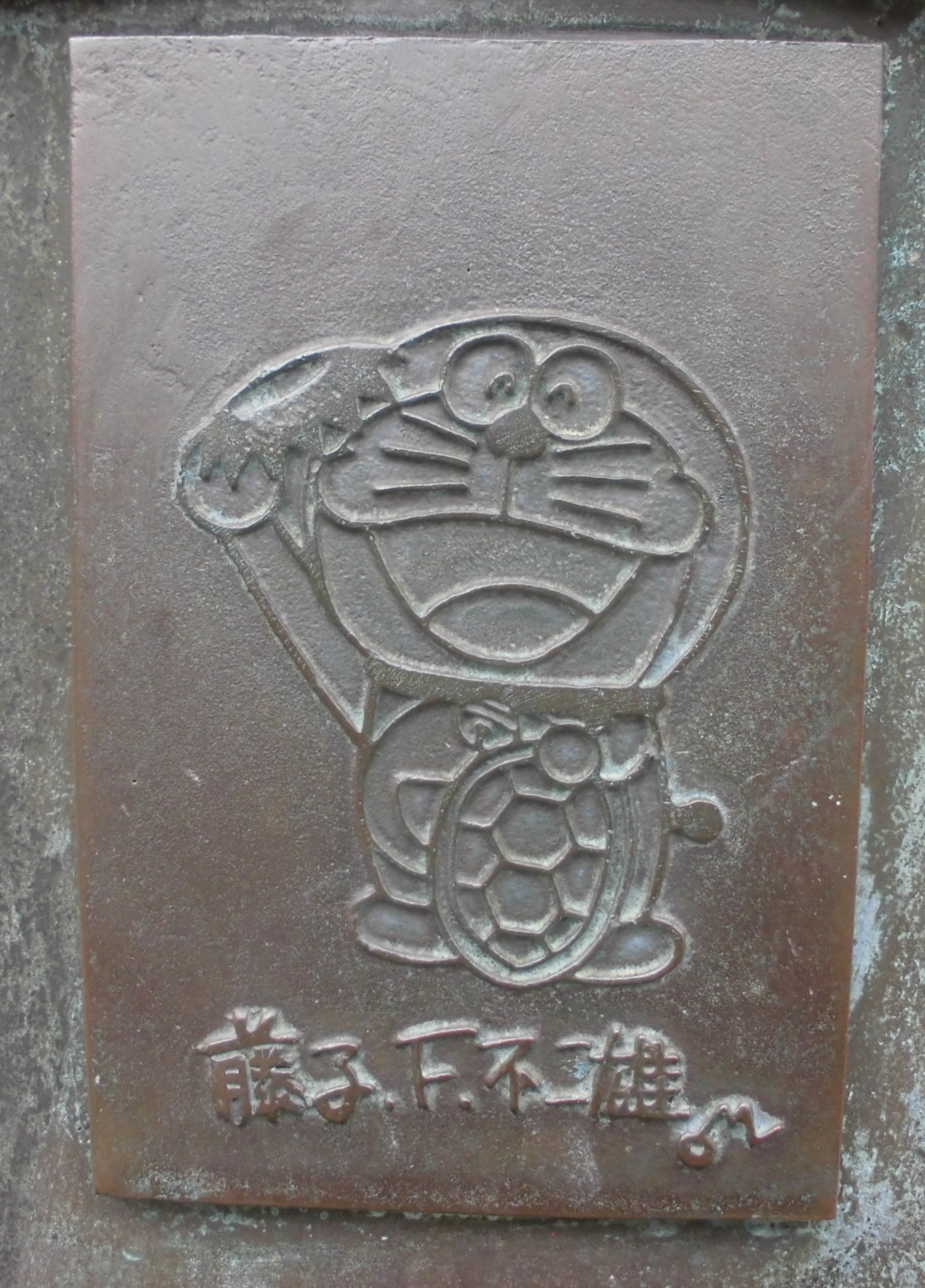 銅像の一部に河童の恰好をしたドラえもんの絵が彫られている写真