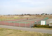 広々とした河川敷に3面横に並んで作られているテニスコートの写真