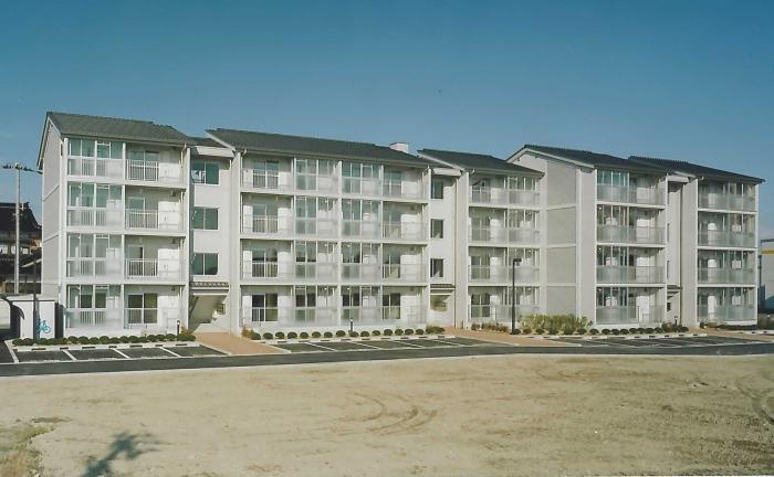 駐車場の後ろに立つ新しい4階建ての建物の写真