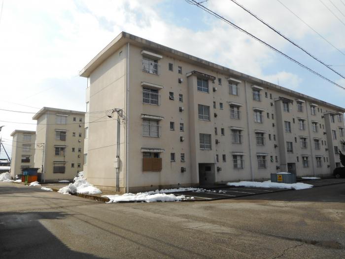 クリーム色の4階建ての建物が3つ並んでいる様子の写真