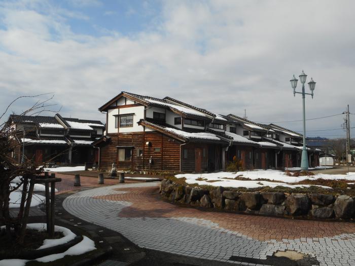 板張りの壁の家に雪が積もっている写真