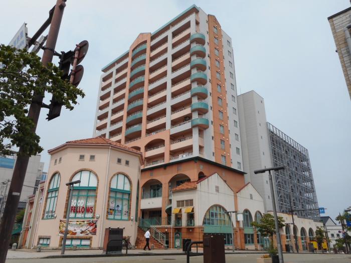 低層階に店舗の入った明るい配色の高層ビルの写真
