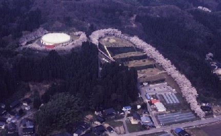 山の中にあるドーム型の施設と隣接する公園からなる国吉配水場を空から俯瞰する写真