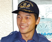 高岡市消防団のキャップをかぶった畑 志歩さんがやや斜め方向に目を向け笑顔でいる様子の写真