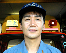 キャップを被った細身の森 昌晃さんが車庫のような場所で正面を向いている様子の写真