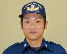 高岡市消防団のキャップと制服を身に着けた村田 祐真さんが正面を向き視線を真っ直ぐこちらへ向けている様子の写真