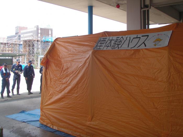 「煙体験ハウス」と書かれたオレンジ色のテントの写真