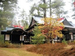 紅葉する樹々に取り囲まれた日本家屋の写真