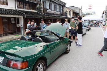 土蔵造りの住居の前に、緑のコンバーチブルの車が置かれている写真