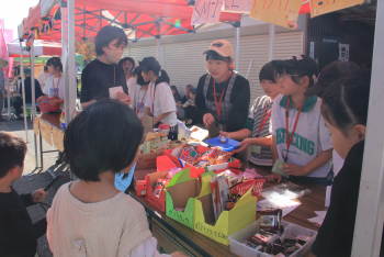 駄菓子を売る体験をする少女の写真
