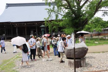 大きな御堂の前の庭で、観光客たちが思い思いに散策を楽しんでいる写真
