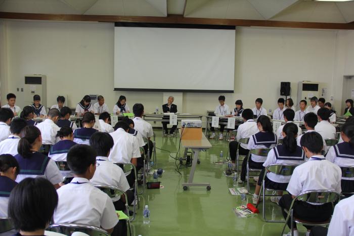 二上まなび交流館第1研修室にて、一番前で座って講演を行なっている高岡市長の話を聞く、高岡市内12の中学校の生徒会の生徒達の写真