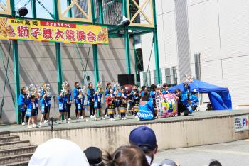 青い法被を着た老若男女が、舞台に上がって、イベントをしている写真