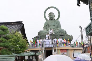寺の屋根の向こうに、巨大な大仏像が見えている写真