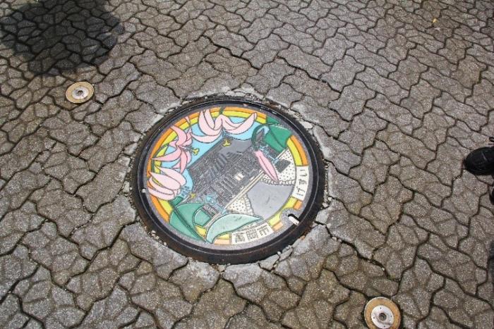 寺社の周りに花が描かれた高岡市のご当地マンホールの写真