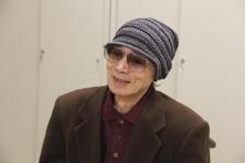 帽子と色付き眼鏡を着用した、笑顔で話す岬坊昌明さんの写真