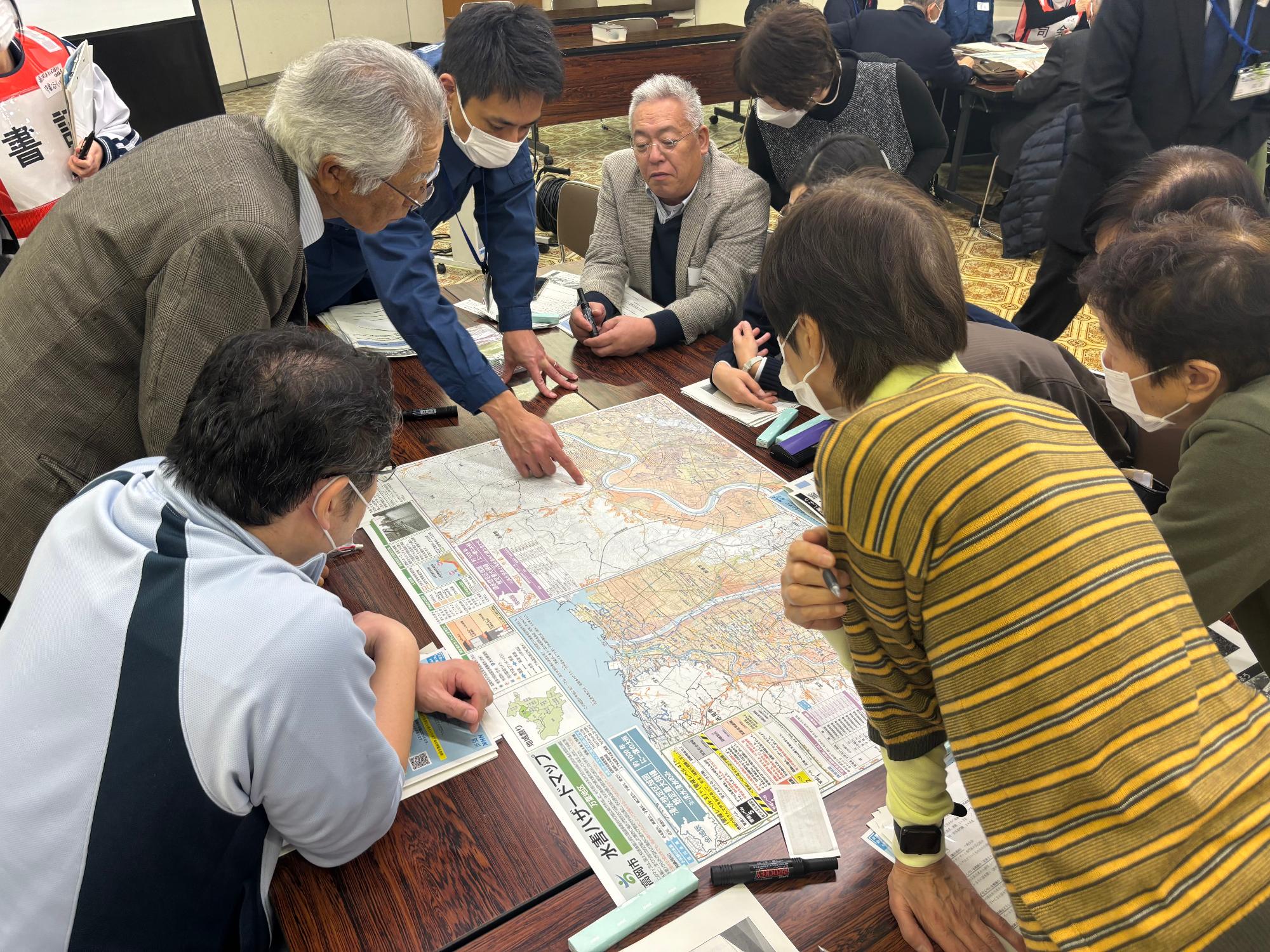 自治会長や民生委員などが地図を見ながら避難計画を話し合う様子