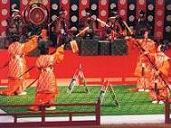 朱色の装束を着た4人の人々が舞台上で舞を演じている写真