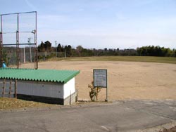 野球のグラウンド手前に併設されているトタン屋根の建物とフェンスがある写真