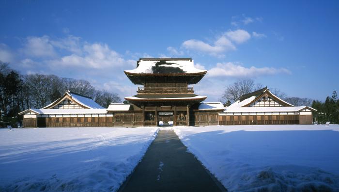 青空を背景にした瑞龍寺と瑞龍寺へ続く雪かきのされた道の写真