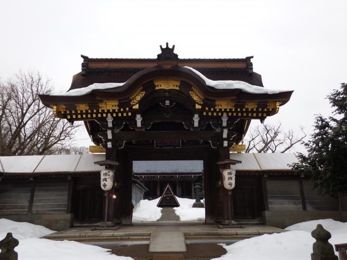 雪が積もる中勝興寺の門を正面から収めた写真