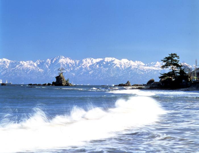 雪化粧した立山連峰を遠くに望む、有磯海の全景写真