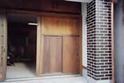 修理を終えて復元された、建物正面の揚げ戸の写真。写真右側には同じく修理されたレンガの防火壁も確認できる