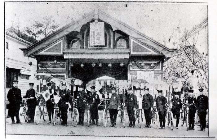 1917年当時の警察庁舎と、その前に横一列で並ぶ防火宣伝隊をおさめた古写真