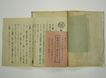 色褪せた紙に文章が書かれ、文字の書かれた赤い紙と緑の紙が差し込まれている写真
