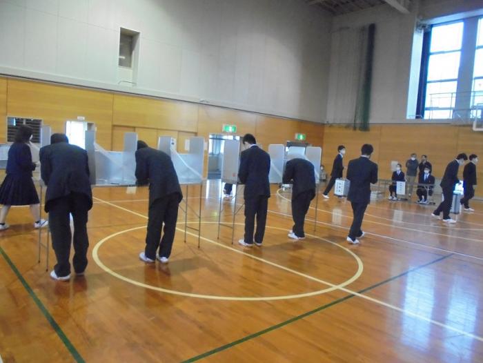 模擬投票で投票用紙に記入している高岡工芸高等学校の生徒たちの写真
