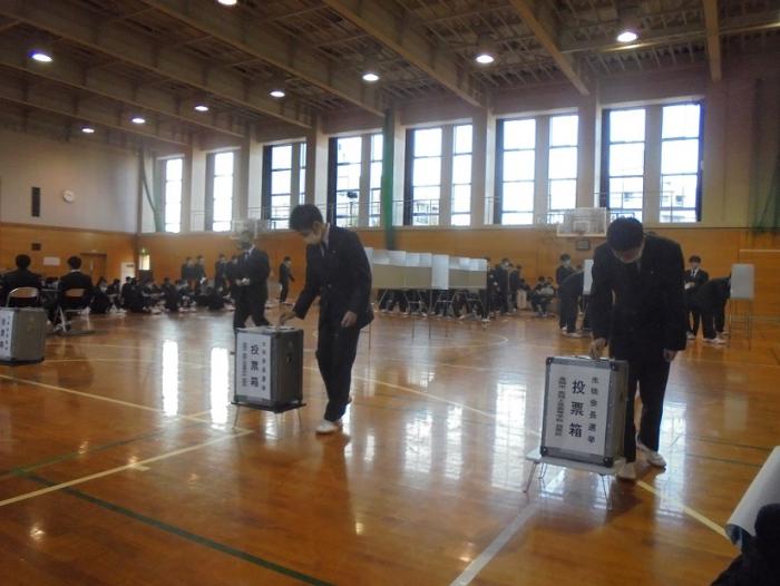 模擬投票で投票箱に投票用紙を入れている高岡工芸高等学校の生徒たちの写真