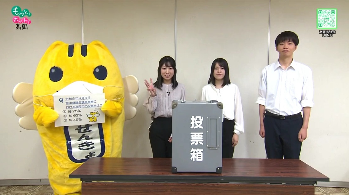 投票箱と共にマスクを着用しためいすいくんと高岡市選挙啓発サポーターT-voiceのメンバー3名の写真