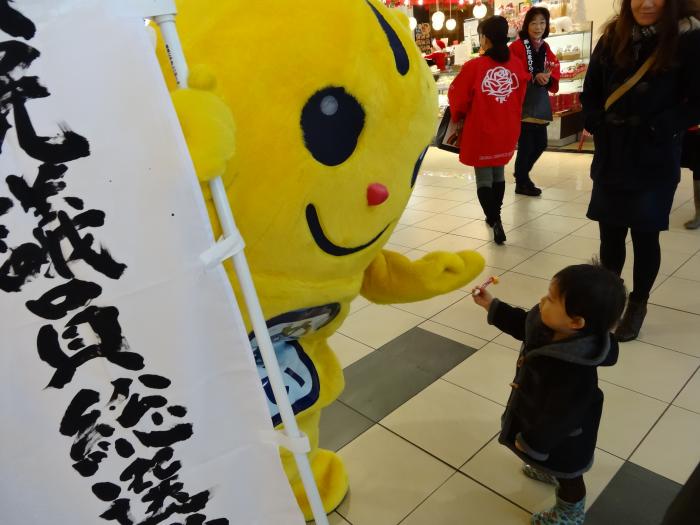 衆議院議員総選挙ののぼりを片手にしつつ、街中の子供とハイタッチを交わす「めいすいくん」の写真